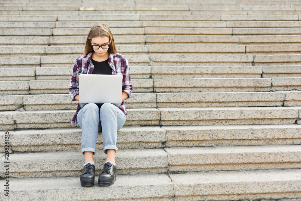 Serious student sitting on stairs using laptop Serious student sitting on stairs using laptop