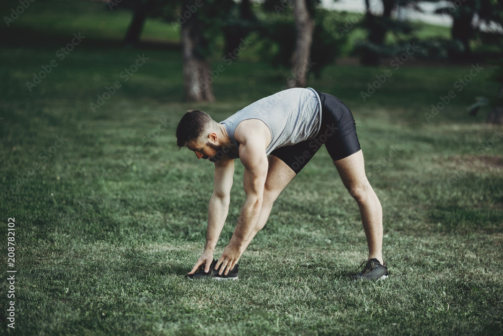 Runner doing stretching exercise before jogging Runner doing stretching exercise before jogging
