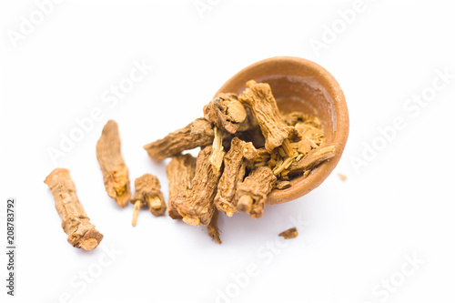 Raw dried Indian sarsaparilla in a clay bowl isolated on white used in many or almost Indian Asian flavored beverages. photo