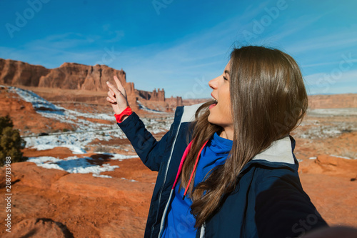 Female traveller taikng self portraits with rock formation in the Arches National Park, Utah, USA photo