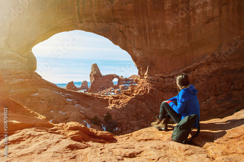 Young woman traveler enjoying the natural beauty of the Double Arch rock formation in Arches National Park.