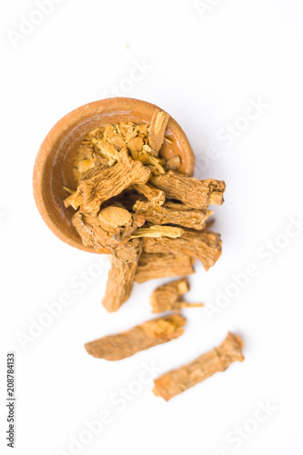 Raw dried Indian sarsaparilla in a clay bowl isolated on white used in many or almost Indian Asian flavored beverages. photo