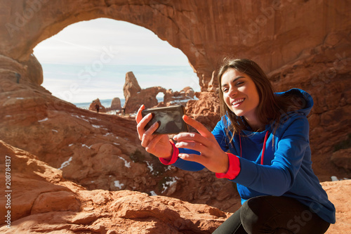 Fotografia Female traveller taikng self portraits with rock formation in the Arches Nationa