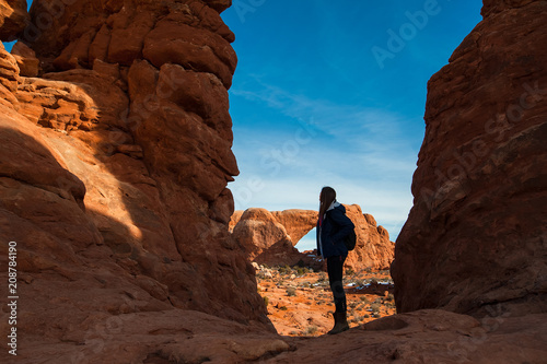 Young woman traveler with backpack hiking the Turret Arch, Arches National Park in Utah