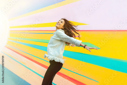 Joyful young woman on the street jumping on air looking happy and enjoying the time outdoor.