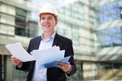 Smiling male architect in helmet with documents © JackF