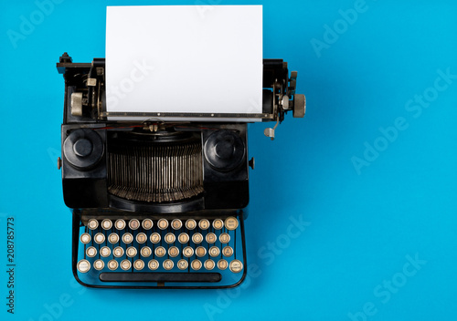 Vintage typewriter top down flatlay shot from above with empty, blank sheet of paper on cyan photo