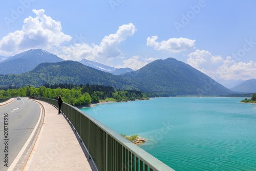 young woman at bridge at Sylvensteinsee in summer enjoying view