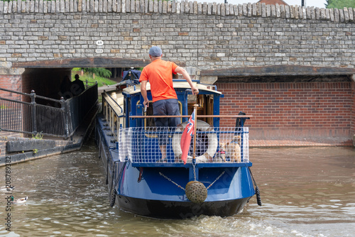 blue and cream canal boat being driven through small gap in tunnel under bridge in a tight fit photo