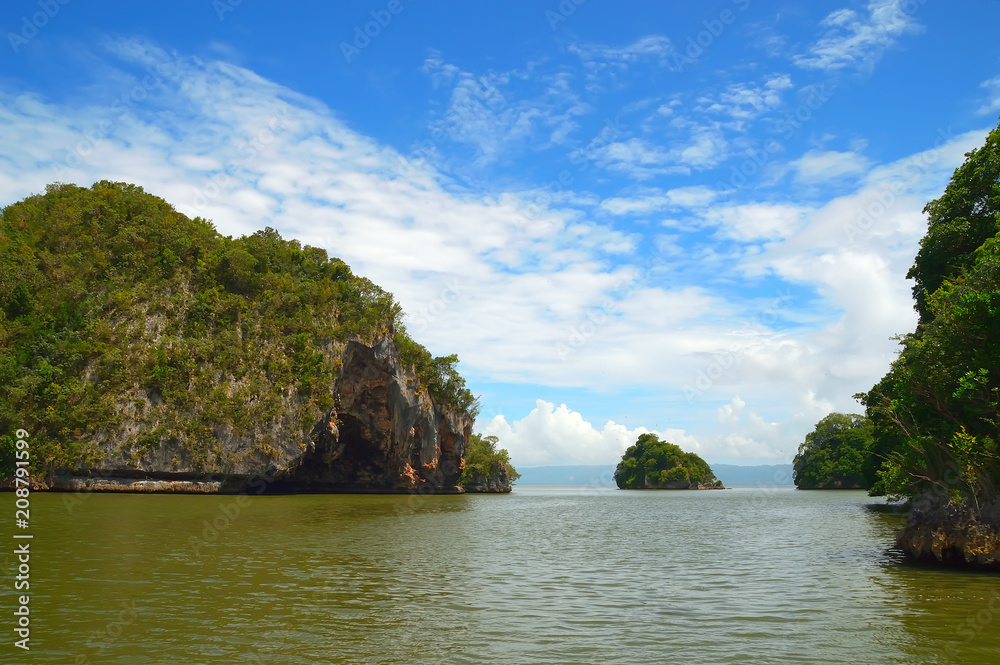 Obraz premium island, rock in the Atlantic Ocean covered with green vegetation, against a backdrop of the shore in the background