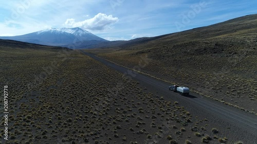 Van and trailer, motorhome in steppe, argentina riding on a gravel lonely road. Wyle mountain with snow at background. National Park. Aerial drone scene moving left and going upwards tracking car photo