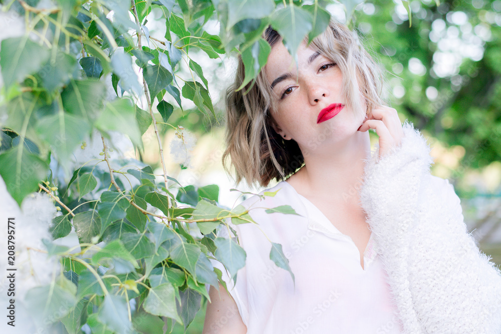 Young attractive woman with red lips in white casual clothes walking posing in the park Young attractive woman with red lips in white casual clothes walking posing in the park