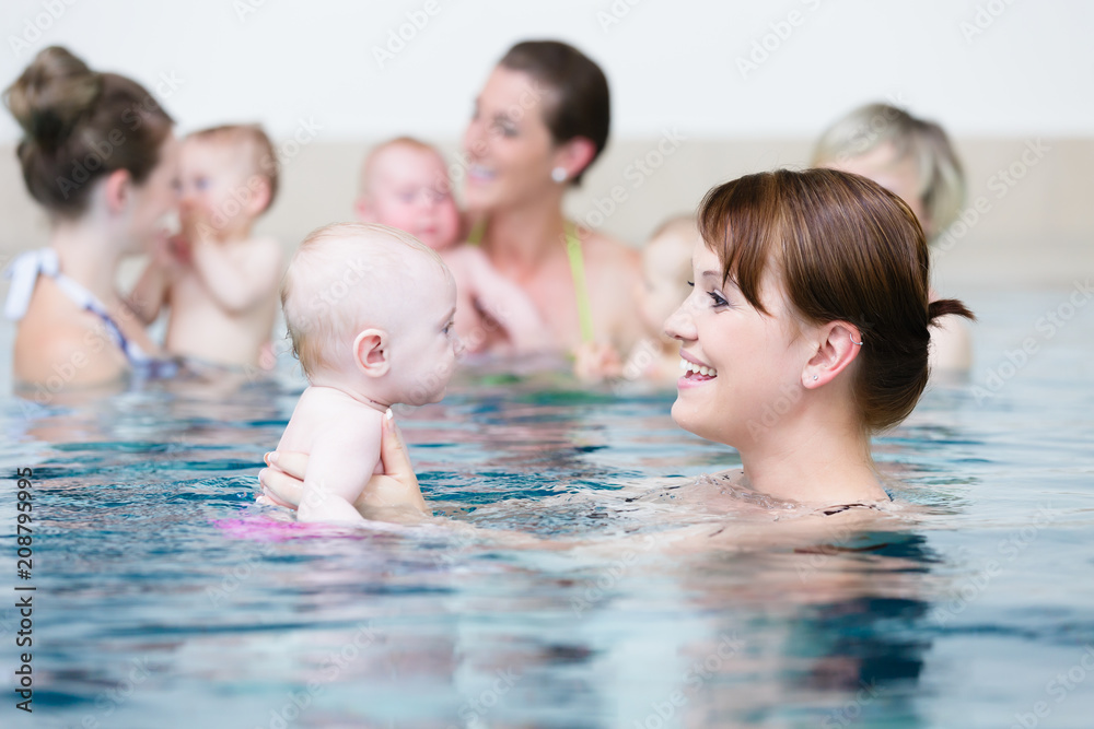 Group of mums with their baby children at infant swimming class Stock