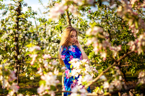 girl - spring in the garden of apple trees in a dress with long hair and brown eyes through the branches