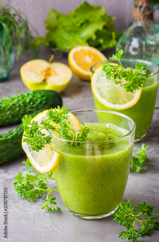 Refreshing smoothies from cucumber, green apple, fresh herbs and lemon juice in transparent glasses on the table. The concept of a healthy diet. Vegetarian menu