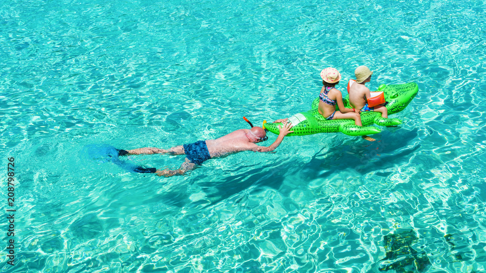 A father spending funny moments with his kids on the sea of Mallorca, in summer holiday.