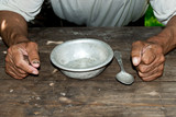 Poor old man's hands and empty bowl on wooden background.An angry hungry man clenches his hands into fists. the concept of hunger or poverty. Selective focus.Homeless. Alms