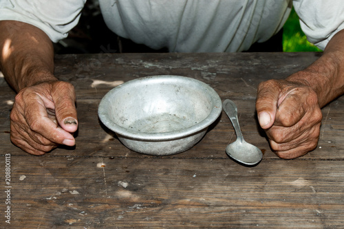 Poor old man's hands and empty bowl on wooden background.An angry hungry man clenches his hands into fists. the concept of hunger or poverty. Selective focus.Homeless. Alms