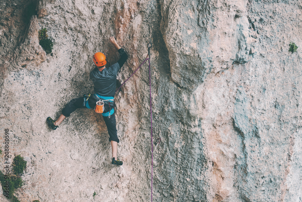 A man in helmet climbs the rock. A man in helmet climbs the rock.