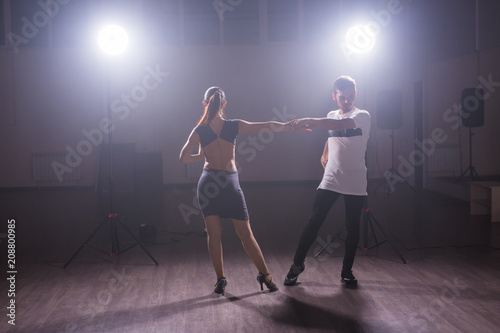Skillful dancers performing in the dark room under the concert light and smoke. Sensual couple performing an artistic and emotional contemporary dance © satura_