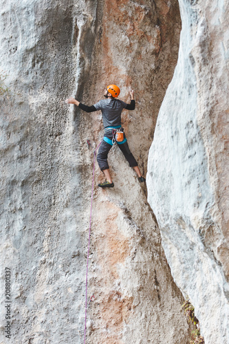 A man in helmet climbs the rock.