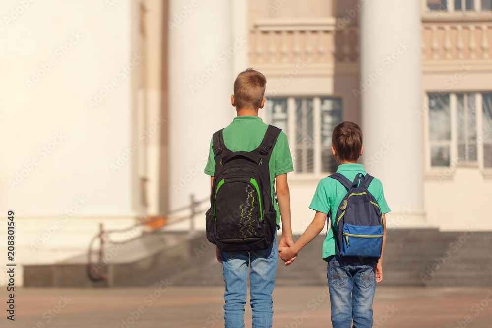 Two school kid boys with backpack on sunny day. Happy children go to school. Back view