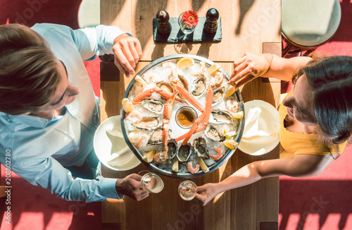 Junges Paar stößt mit Sekt in trendigem Restaurant an  photo