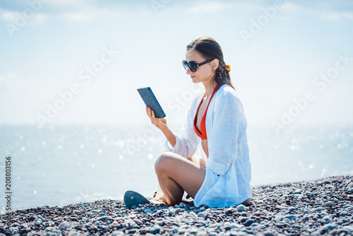 Frau liest einen Roman als e-book am Strand