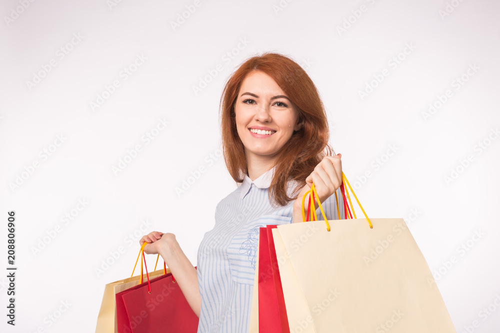 Portrait of young happy red-haired woman with shopping bags on white background Portrait of young happy red-haired woman with shopping bags on white background