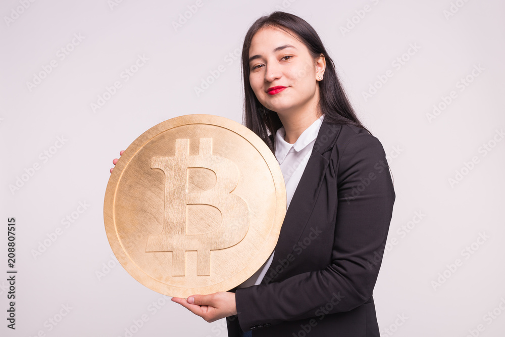Asian woman holding big bitcoin on white background. Cryptocurrency investment concept. Asian woman holding big bitcoin on white background. Cryptocurrency investment concept.