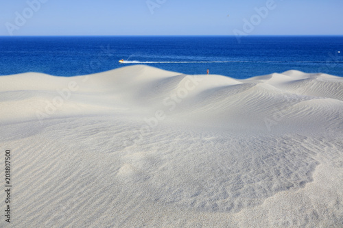 Biała piaszczysta wydma nad brzegiem błękitnego morza, oceanu.