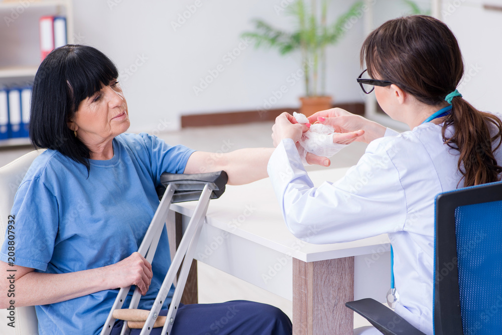 Fototapeta premium Doctor examining old mature woman after incident