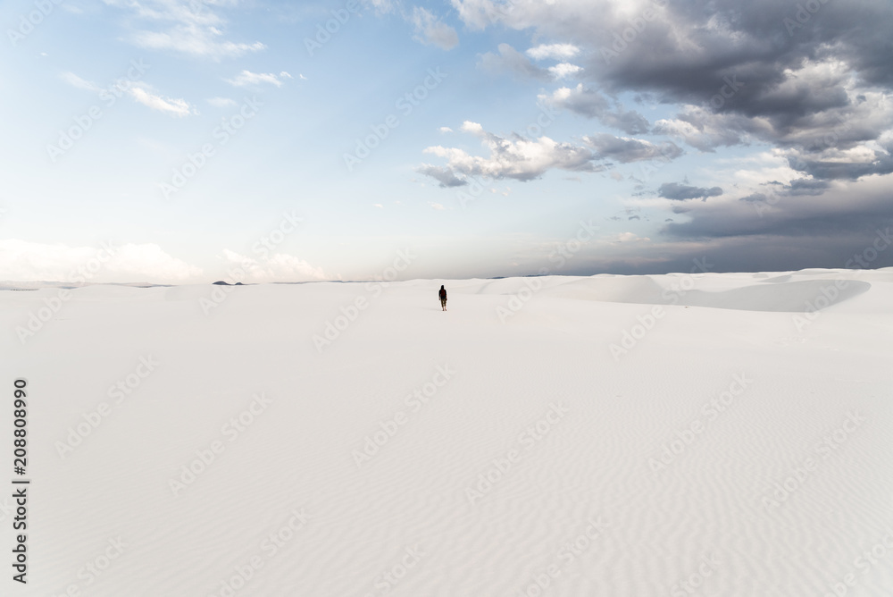 A man standing on top of a sand dune at White Sands National Monument in Alamogordo, New Mexico. 