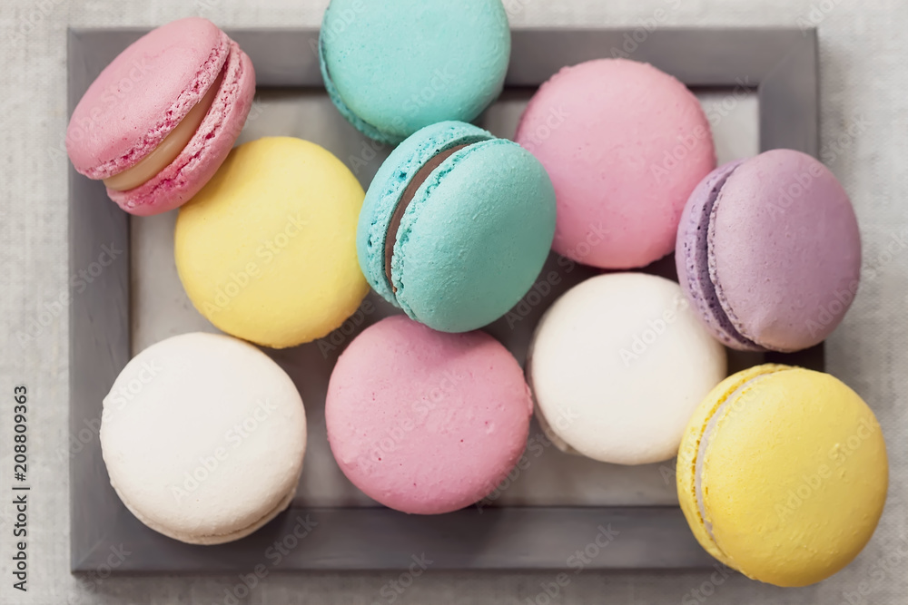 Obraz premium Fresh natural colorful macarons of different tastes in wooden frame, unusual abstract sweet art, gourmet picture