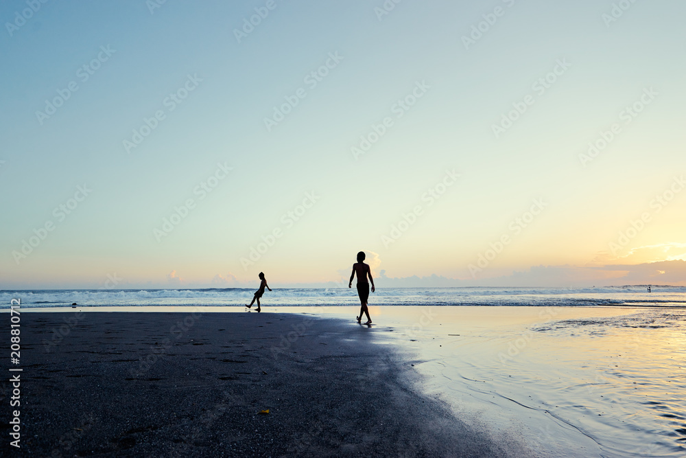 Kids playing on the beach. Sunset on the sea shore. Bali, Indonesia.