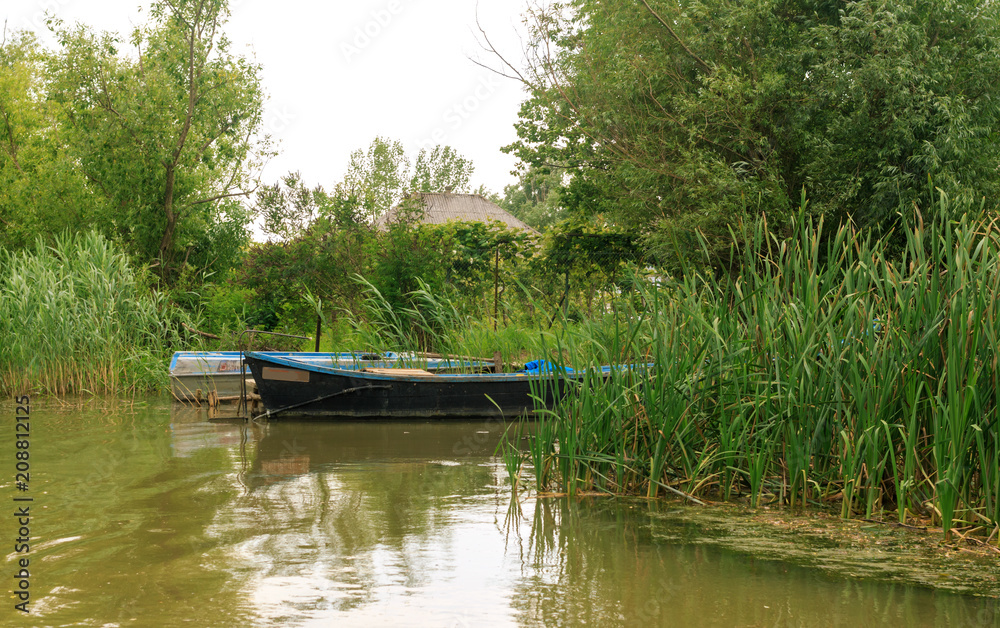 Danube river and fishing boat near the shore on a summer day. Vilkovo, Ukraine