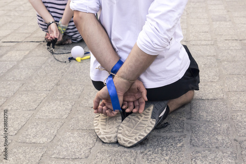 Two people with their hands tied behind their backs sit on their knees in the city square, a social protest against repression and the prohibition of freedom of speech