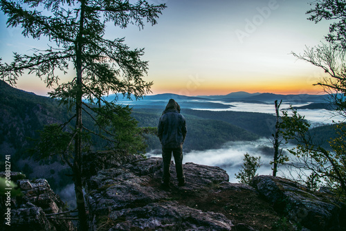 Man hiker standing back on peak of mountains and enjoy to see beautiful landscape view of rocks and mist coming up at summer morning.