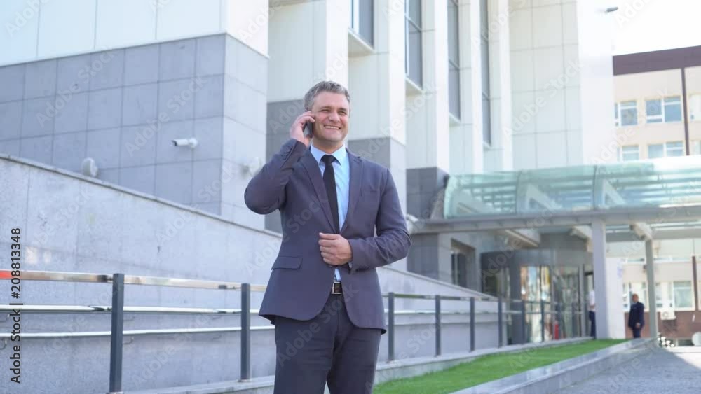 Attractive middle-aged man. Serious businessman Talking on the phone An image of a general plan, against the background of modern office buildings. A solid man in a jacket and tie 4K Attractive middle-aged man. Serious businessman Talking on the phone An image of a general plan, against the background of modern office buildings. A solid man in a jacket and tie 4K