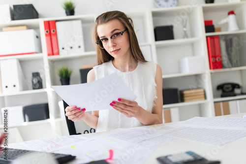 A young girl in the office is holding a sheet.