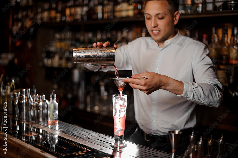 Smiling barman making a fresh and cold strawberry mojito summer cocktail