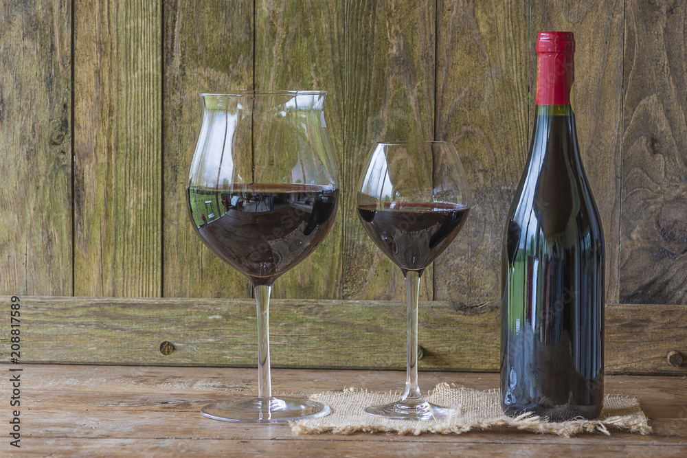 Bottle and two glasses of red wine on rustic wooden background with copy space