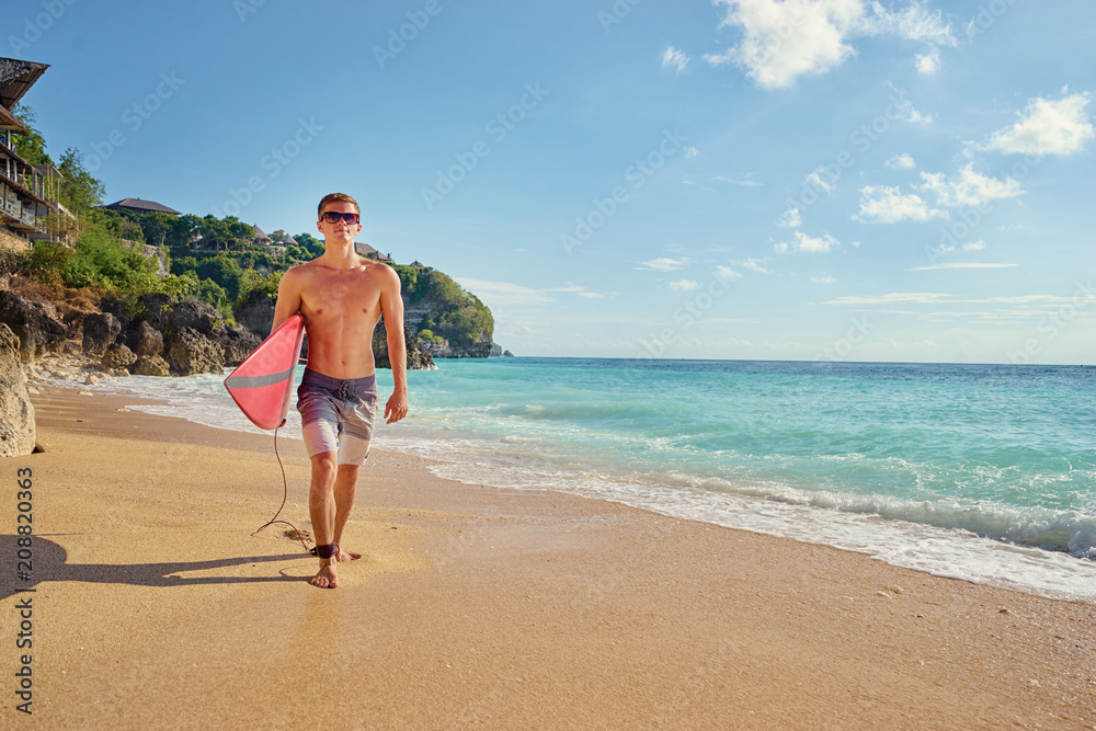 Hobby and vacation. Holiday on the beach. Young man carruing surf board. Hobby and vacation. Holiday on the beach. Young man carruing surf board.