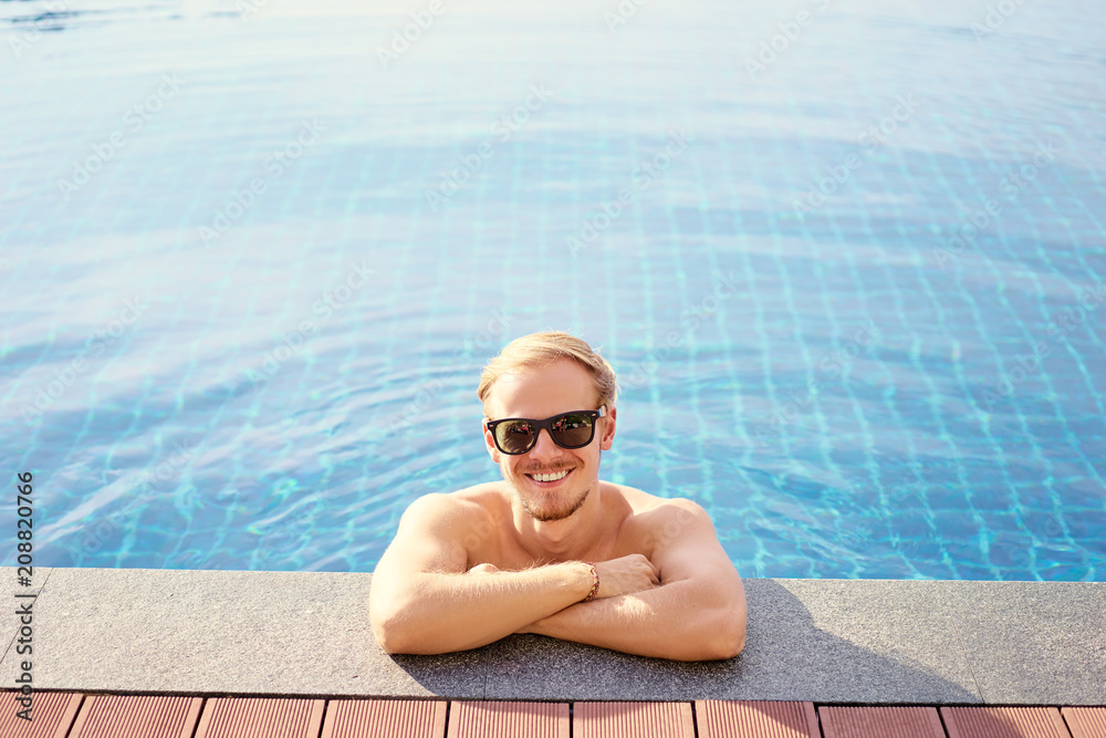 Vacation concept. Happy young man at swimming pool.