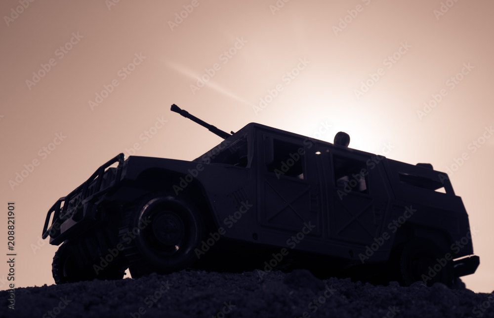 Military patrol car on sunset background. Army war concept. Silhouette of armored vehicle with gun in action. Decorated.