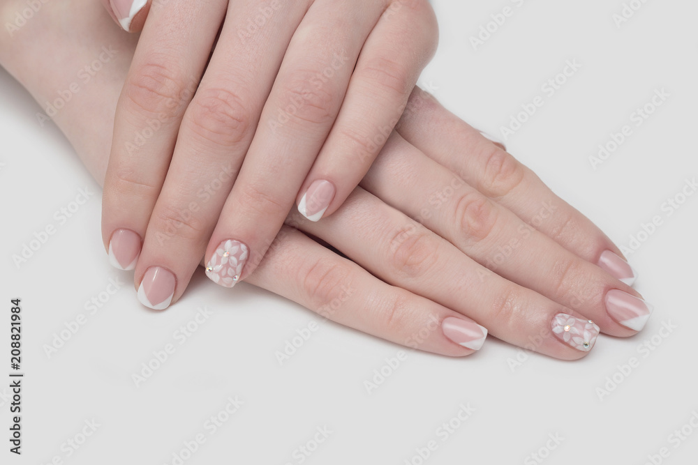 Manicure with rhinestones in the shape of hearts and pink balls on white and red nail Polish on a white background. Manicure with rhinestones in the shape of hearts and pink balls on white and red nail Polish on a white background.
