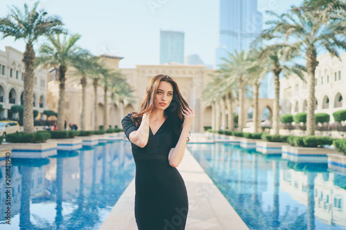 Photography Beautiful young woman with charming smile and long hair walking on Dubai Downtown