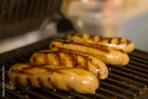 fried meat sausages with grill bars, four appetizing sausages on gridiron background