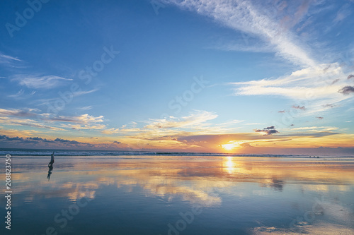 Beautiful sunset on ocean beach. Sky is reflecting at water.