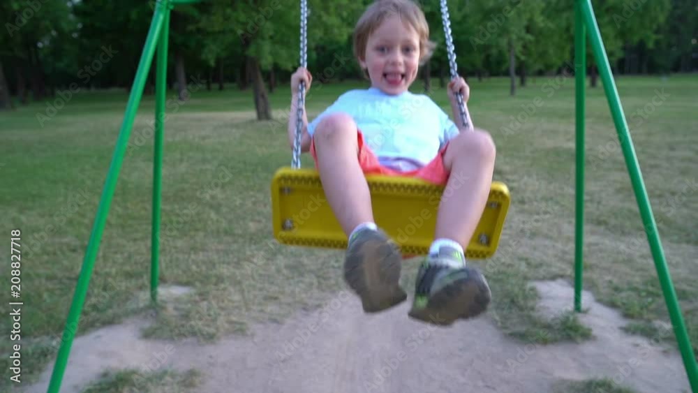 Caucasian baby boy playing on a swing and having fun in park Caucasian baby boy playing on a swing and having fun in park